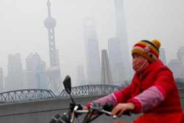 امرأة تقود دراجة في يوم ترتفع فيه مستويات تلوث الهواء في شنغهاي بالصين